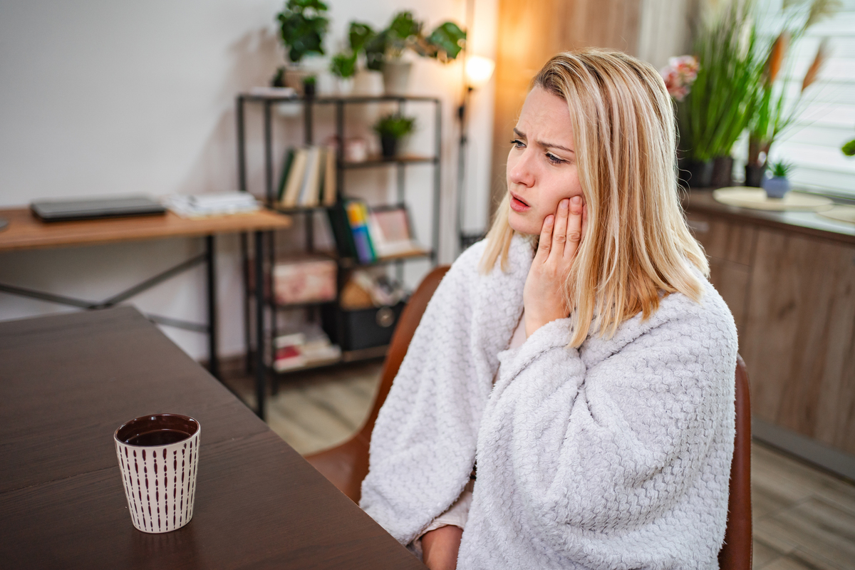 Woman experiencing tooth pain delaying emergency dental care